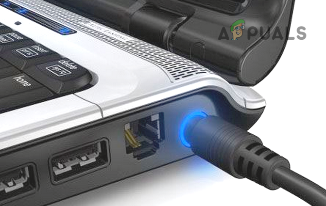 Close-up of a laptop's charging port with a glowing blue light indicating the power adapter is connected